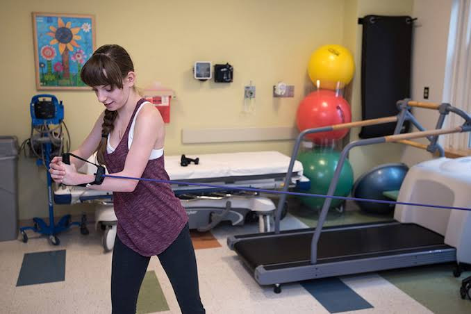 A young patient practices a resistance-band exercise in Boston Children’s Cardiac Fitness Program